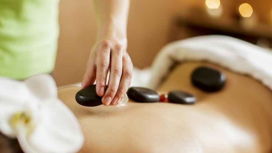 Heated stones are placed along the spine, shoulders, and lower back to target deep muscle tension